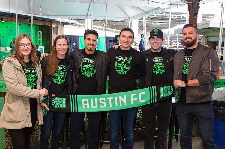 Graduate students holding an Austin FC flag