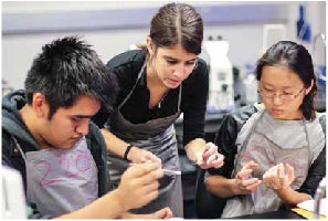 Teacher and two students inspecting materials in a lab