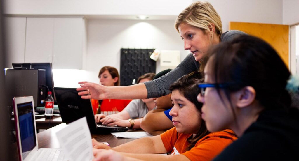 Teacher instructing students on computer