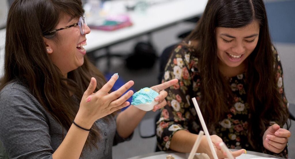 Two young women laugh while making pastries