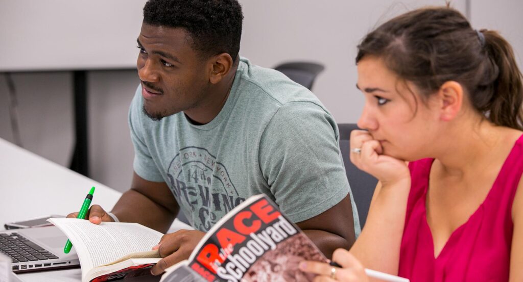 Two students examine their books, Race in the Classroom