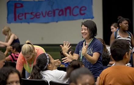 A teacher laughs with her students before an assembly.