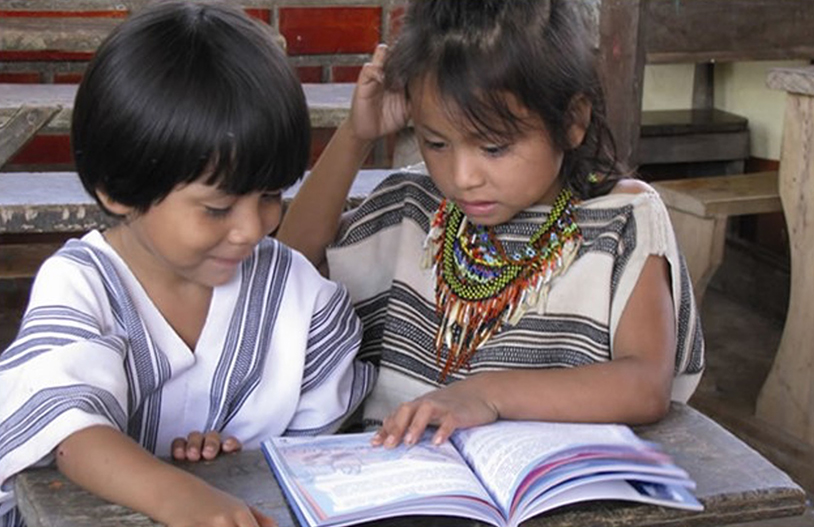 Two young children read a book together