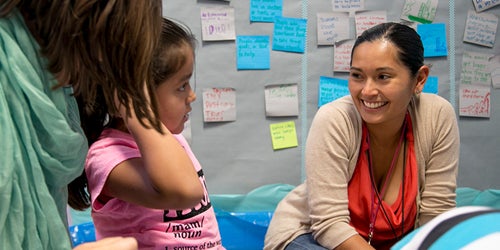 A student teacher works with a young girl.