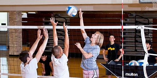 A group of students receiving coaching on how to play volleyball.