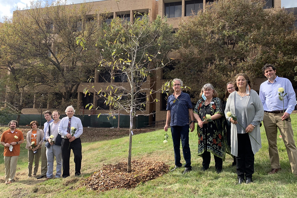 A group of people around a sapling planted near the George I. Sánchez building.