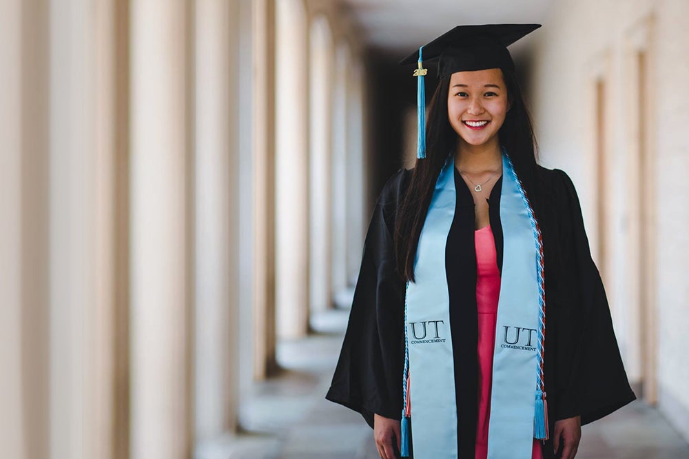 Katy Joa stands in front of the Blanton Museum in her commencement regalia. 