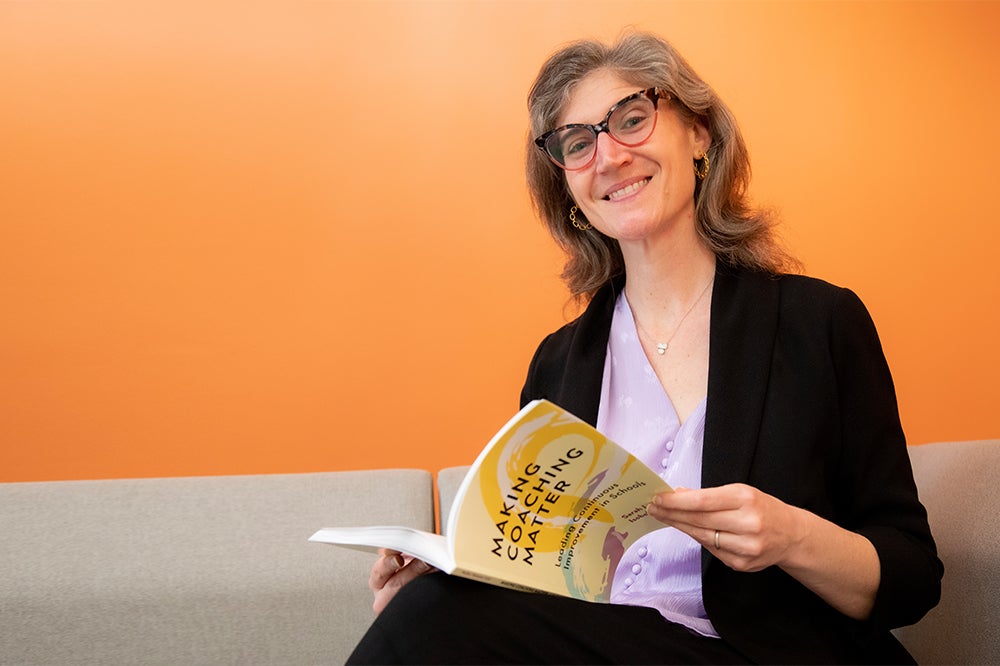 Photo of Sarah Woulfin holding a copy of her new book, "Making Coaching Matter."