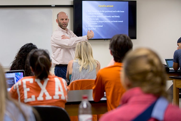 Students listen to a Corey Hannah give a presentation in a classroom setting. 