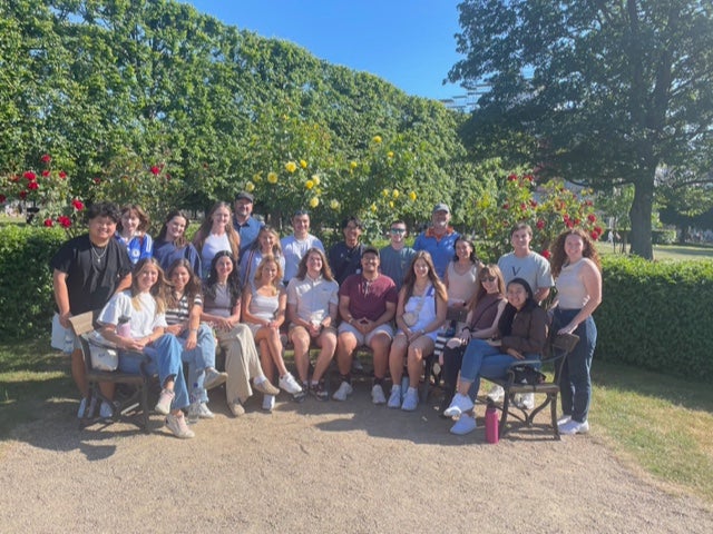 A group of students sit outside for a photo. 