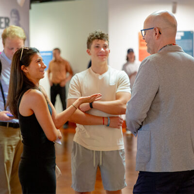 Students network at an event with faculty members