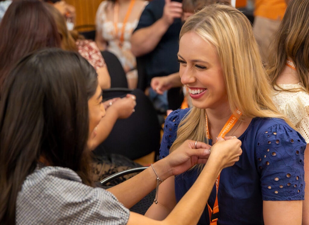 Kelli Mulloy at the Teacher Pinning Ceremony. The fellow student is adding a Longhorn pin to Kelli's lanyard.