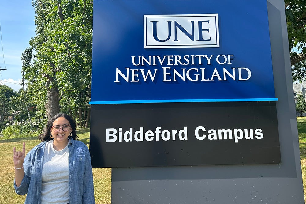 Jillian Sanchez standing next to the University of New England Biddeford Campus sign.