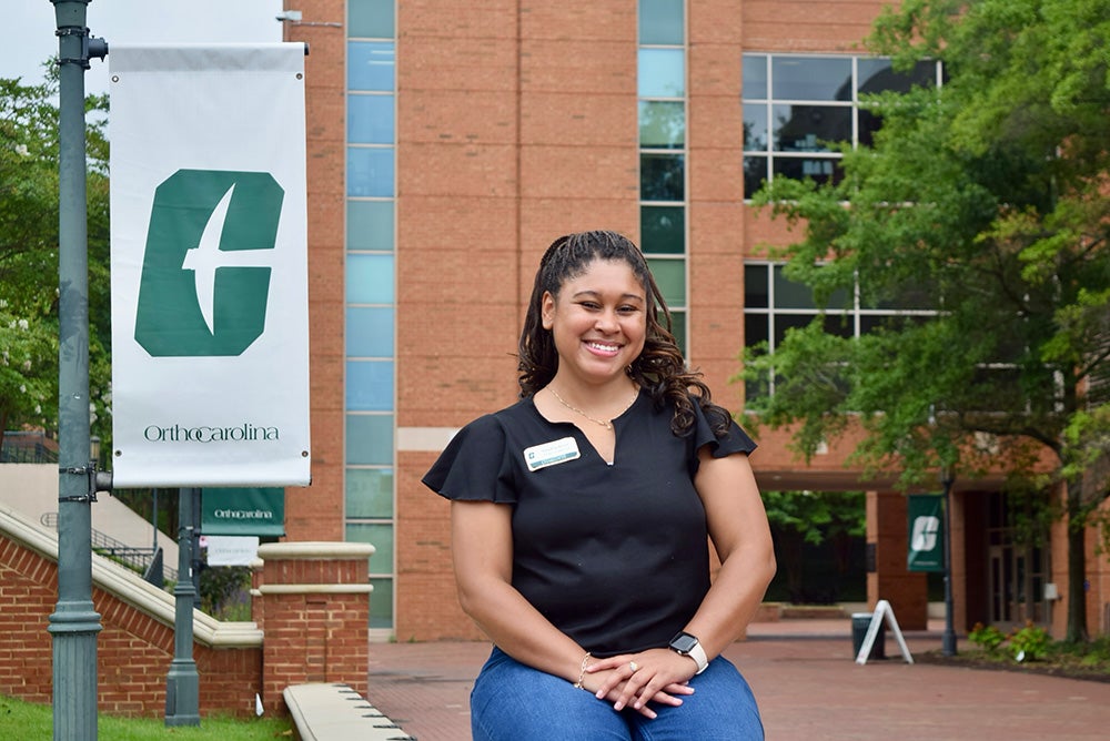 Kandria Knox is sitting in front of a campus building at the University of North Carolina at Charlotte.